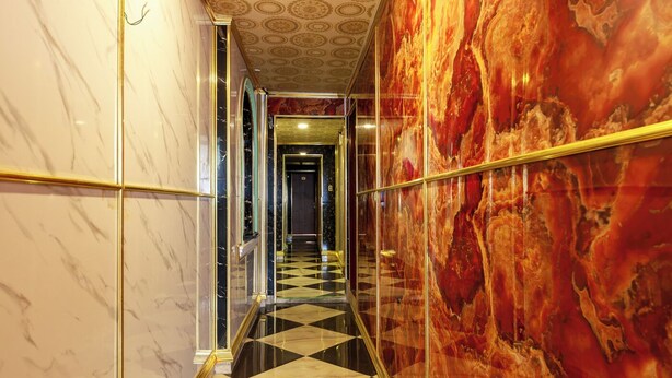 A hallway with marble walls, a checkered floor, and a glass elevator. - Venus Hotel & Massage - Bui Vien Walking (Ho Chi Minh City)