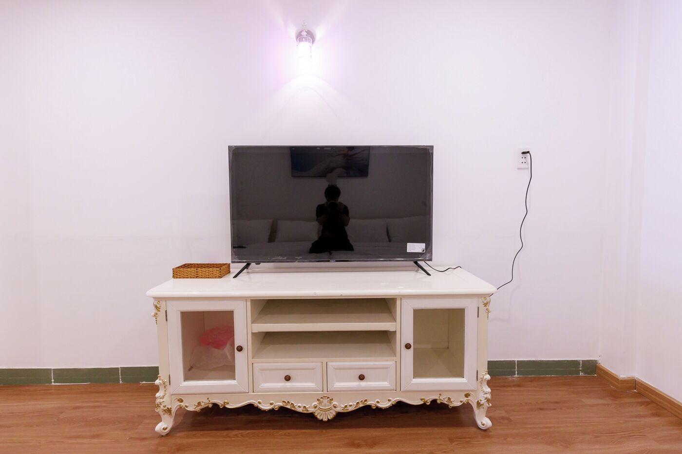 Un mueble de entretenimiento blanco con un televisor de pantalla plana, una cesta y una figura decorativa de un caballo.
