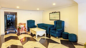 A living room with a checkered floor, a white coffee table, and two blue armchairs. - Venus Hotel & Massage - Bui Vien Walking (Ho Chi Minh City)