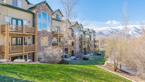 A multi-story hotel with balconies, a well-maintained lawn, and a mountainous backdrop. - 3-bedroom condo in fabulous Eden, skiing, biking, hiking, and water sports (Eden)