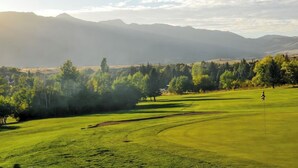 A golf course with a flagstick, surrounded by trees and mountains in the background. - 3-bedroom condo in fabulous Eden, skiing, biking, hiking, and water sports (Eden)