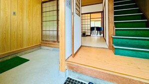Un interior japonés tradicional con puertas correderas de madera, una escalera con escalones verdes y un suelo de tatami.