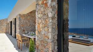 Ein mit Naturstein verkleideter Essbereich im Freien mit Blick auf das Meer.