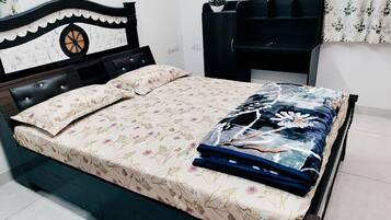 A bed with a floral bedspread, a decorative headboard, and a bedside table with a plant.