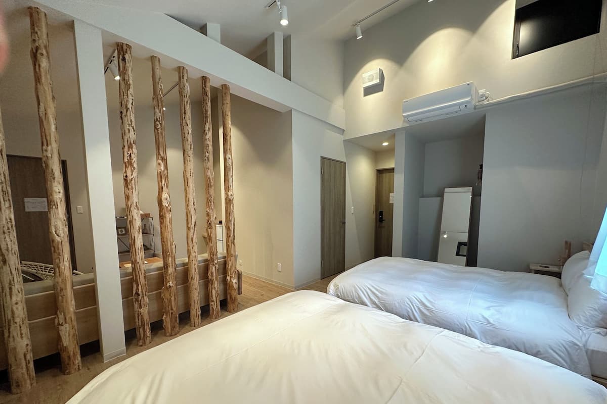 A hotel room with two beds, a wooden staircase, and a modern design.