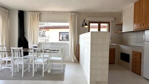 Une cuisine moderne avec des meubles blancs, un coin repas comprenant une table et des chaises, et une vue par la fenêtre.