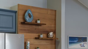 A modern kitchen with a stainless steel refrigerator, a gas stove, wooden shelves with decorative items, and a framed picture on the wall. - Beautiful conveniently located 2-bedroom ocean view home in Kailua-Kona.  (Kailua-Kona)