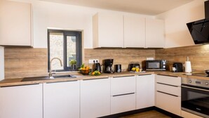 Una cocina moderna con armarios blancos, encimera de madera, pileta, estufa y microondas.