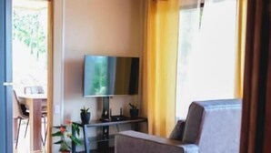 Un salon comprenant un canapé, un téléviseur et un coin repas avec des chaises et une table.