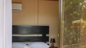 Une chambre d’hôtel avec un lit, une chaise et une fenêtre donnant sur un paysage verdoyant.