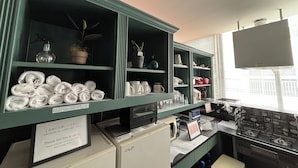 A hotel room with a kitchenette, a TV, and shelves with towels and kitchenware. - LANAI HOTEL AND Dormitory (Naha)