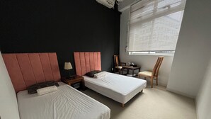 A bedroom with two beds, a nightstand, a chair, and a window with blinds. - LANAI HOTEL AND Dormitory (Naha)