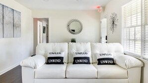 Un sofá de cuero blanco con tres almohadones, cada uno con la etiqueta 'UNPLUG' y 'UNWIND'.