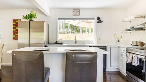 Una cocina moderna con una isla central, electrodomésticos de acero inoxidable y vistas al exterior.
