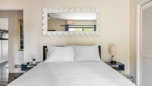 Un dormitorio con una cama grande, un espejo y una mesita de noche con lámpara.