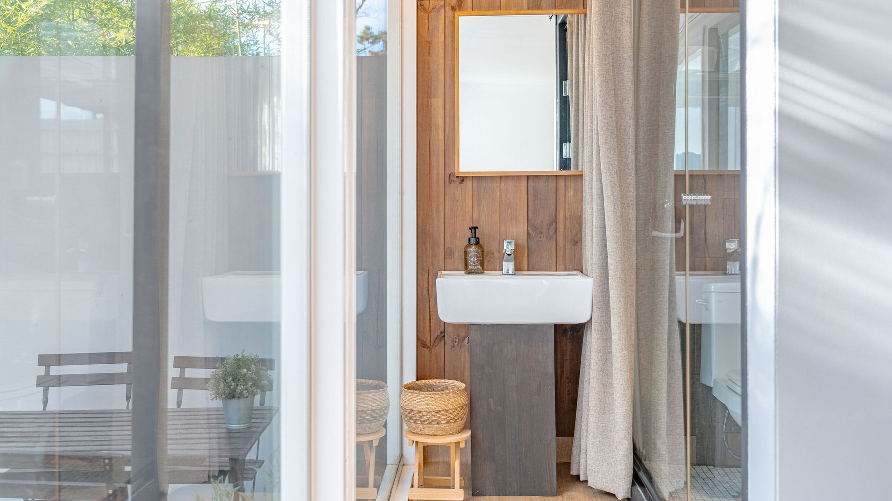 Un baño con tocador de madera, espejo, lavamanos y zona de ducha.