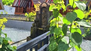 A traditional wooden structure with a tiled roof, surrounded by greenery and a clear sky. - Cool Breeze 2 (Penida Island)