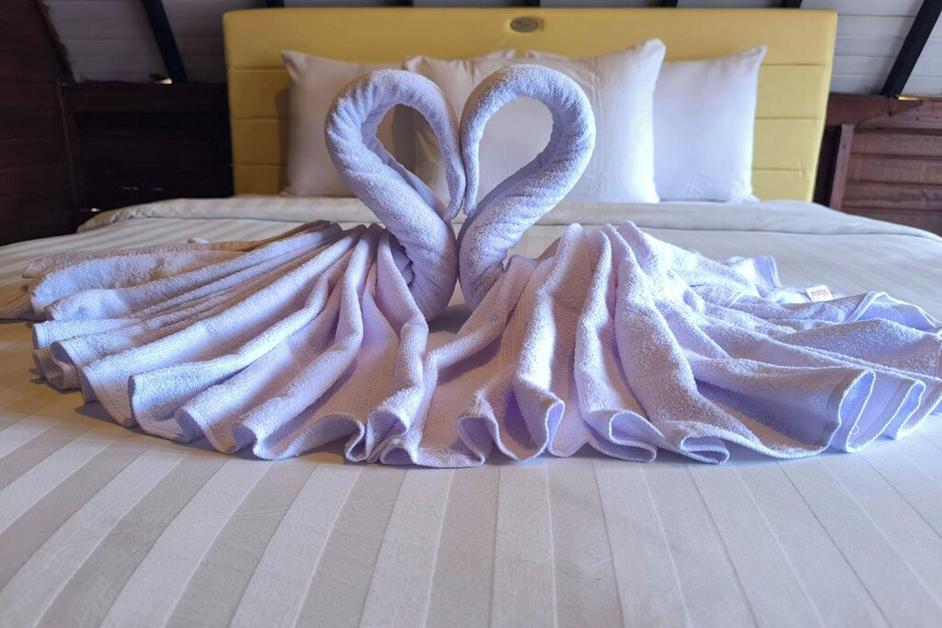 A bed with towels arranged in a heart shape.