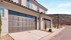 Une maison à deux étages avec un garage, une allée bien entretenue et une vue dégagée sur le paysage environnant.