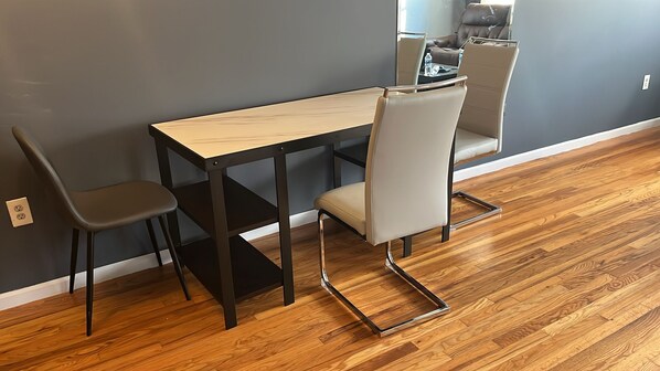 A dining area with a wooden table and two chairs, a sofa, and a coffee table. - NWK 457  ROOM 212-E (Newark)