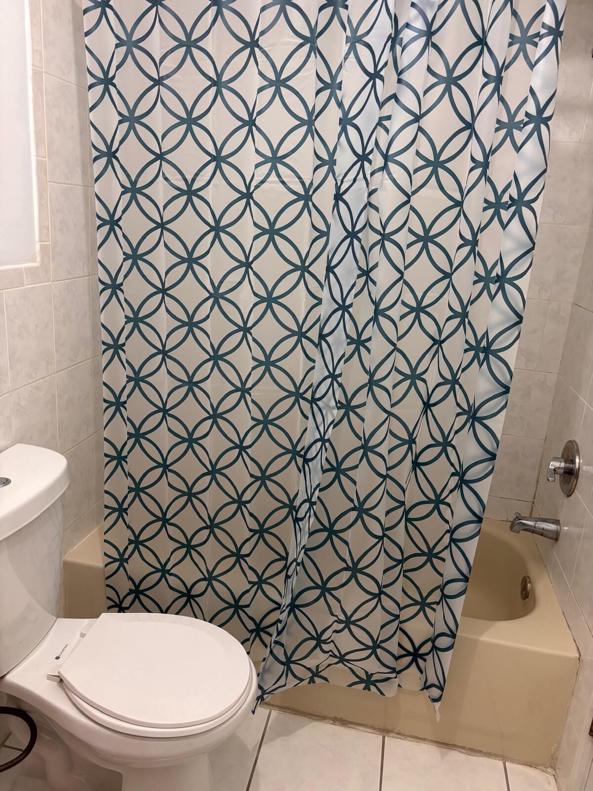 A bathroom with a toilet, a bathtub, and a shower curtain with a geometric pattern.