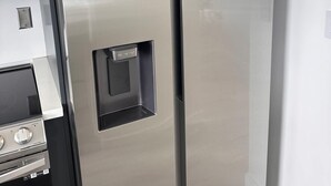 Ein Edelstahl-Kühlschrank mit Wasserspender und integriertem Backofen.