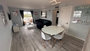 Ein modernes Wohnzimmer mit einer Couch, einem Esstisch mit Stühlen und einer Küchenzeile.