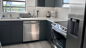 Eine moderne Küche mit grauen Schränken, einem Edelstahl-Geschirrspüler, einem Einbauofen und einer Kaffeemaschine.