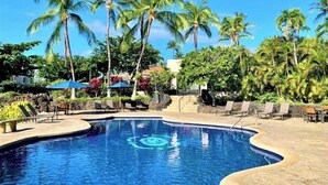 Une piscine entourée de palmiers et de chaises longues.