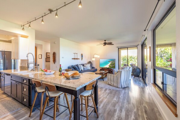 Una cocina moderna con una isla grande, taburetes de bar y un comedor con vistas.