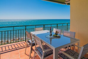 A balcony with a table set for two, overlooking a beach with people in the distance. - La Palomita. Spectacular ocean view (Fuengirola)