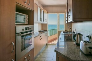 A kitchen with a view of the sea, equipped with a microwave, oven, and a toaster.