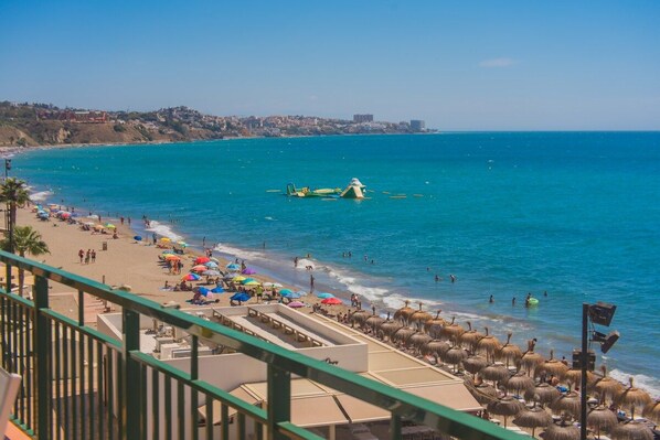 A beach with umbrellas, people, and a clear sky.