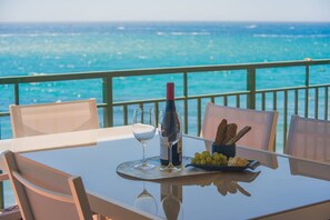 A table with a bottle, glasses, and snacks, overlooking a body of water.