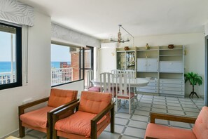 A room with a dining table and chairs, a bookshelf, and a view of the sea. - Benalmadena beachfront location & views (Benalmadena)