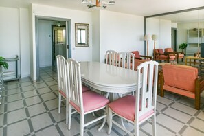 A dining area with a white table and chairs, a mirror on the wall, and a view into another room. - Benalmadena beachfront location & views (Benalmadena)