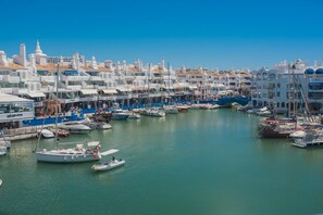 A marina with multiple boats docked, surrounded by white buildings with blue accents. - Large pool, balcony & great views. Parking. (Benalmadena)