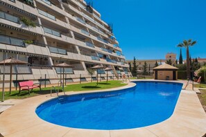 Un hôtel à plusieurs étages doté d’une piscine, d’un espace extérieur aménagé et surplombant un ciel d’un bleu limpide.