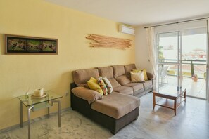A living room with a sofa, a glass coffee table, and a small side table. - Large pool, balcony & great views. Parking. (Benalmadena)
