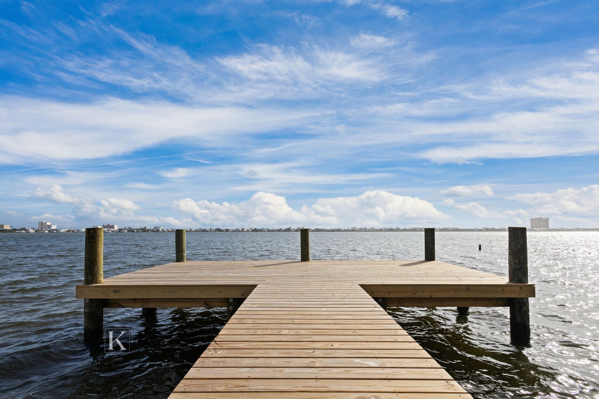 A wooden pier extending into calm water with a clear sky above.