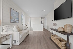 Un salon moderne avec un canapé, un téléviseur à écran plat et des paniers en osier.