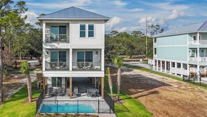 Ein zweistöckiges Haus mit Balkon, Pool und Holzterrasse.