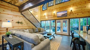 A spacious living room with a sofa, coffee table, and a staircase leading to a balcony.
