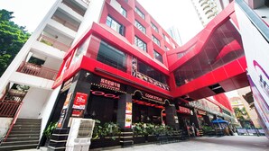 Un edificio moderno con una fachada llamativa en rojo y negro, que cuenta con un restaurante llamado "Cook Steak Bar" en la planta baja.
