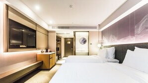 Habitación de hotel con una cama grande, televisor montado en la pared, escritorio y armario.