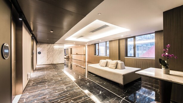 Un moderno vestíbulo de hotel con piso de mármol, una mesa de recepción, un sofá y un amplio ventanal con vistas a la ciudad.