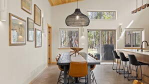 A spacious dining area with a long table, multiple chairs, and a hanging light fixture.