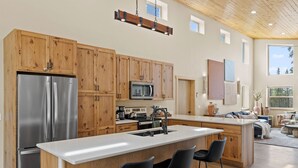 A modern kitchen with wooden cabinets, stainless steel appliances, and a central island with bar stools.