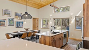 A modern kitchen with wooden cabinets, a large island, and artwork on the walls.