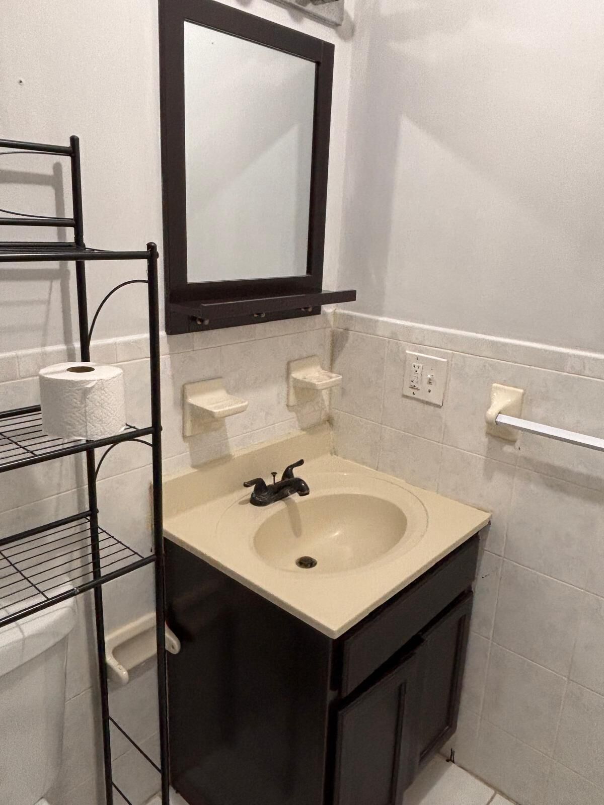 Une salle de bain avec un lavabo, un miroir et des étagères.